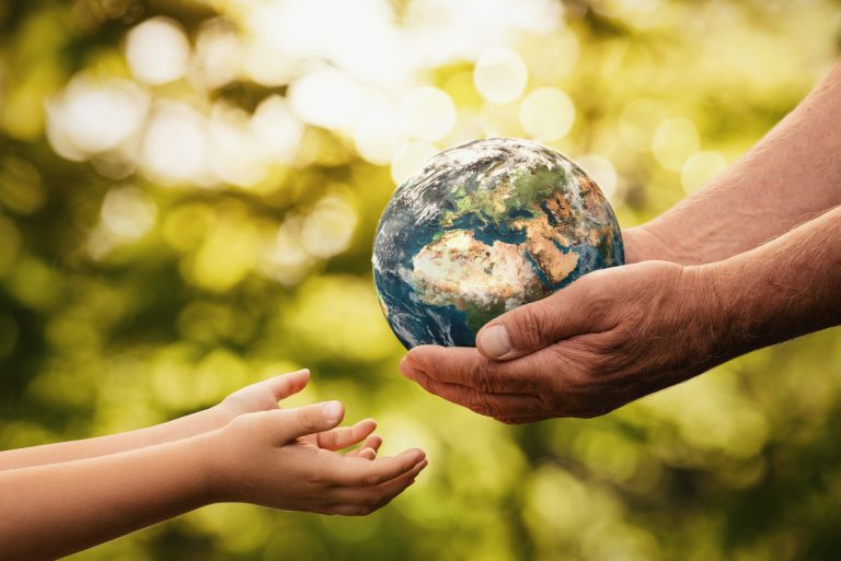 Senior hands giving small planet earth to a child