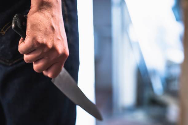 image of a robbers hands holding a knife in the shadows